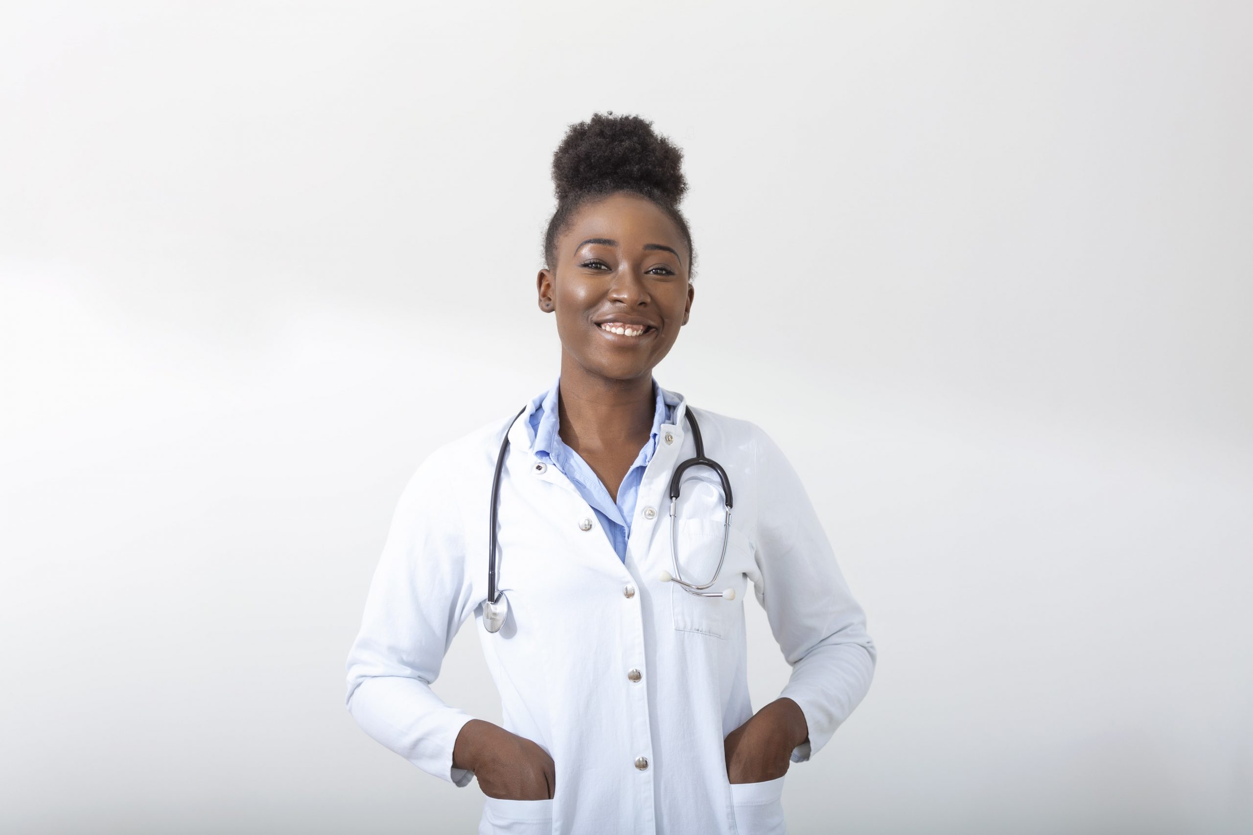 medico-com-uma-mao-de-estetoscopio-no-bolso-close-de-uma-mulher-sorrindo-em-pe-em-linha-reta-no-fundo-branco-min